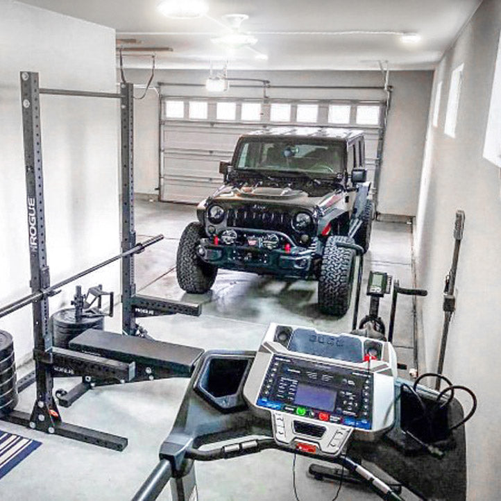 Garage interior featuring a gym area and a parking area with a black jeep. Entire room lit up by an MPI by STKR.